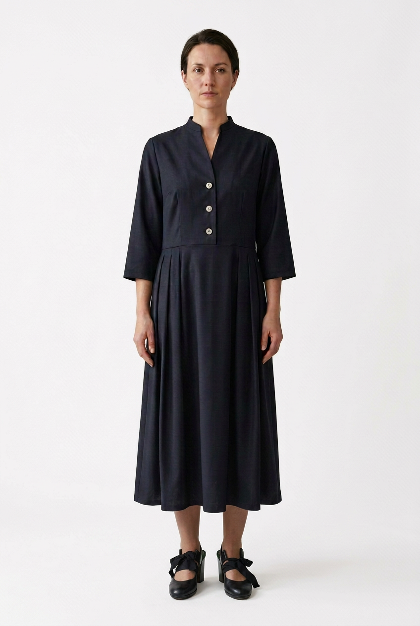 Frisian-Kleid am hellhäutigen Model mit schwarzen Schleifenschuhen vor weißem Hintergrund